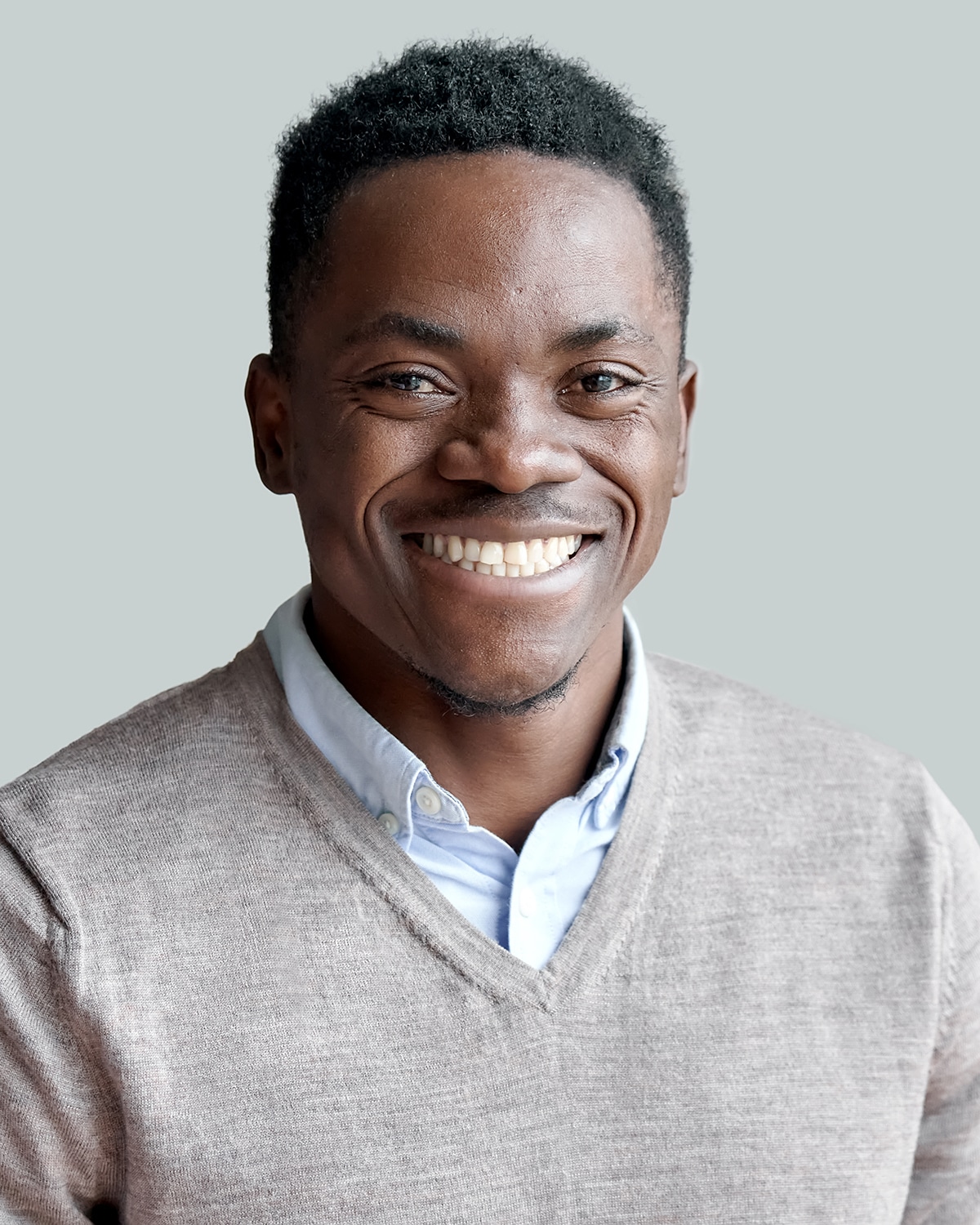 Smiling cheerful young adult african american ethnicity man looking at camera standing at home office background. Happy confident black guy posing for headshot face front close up portrait.