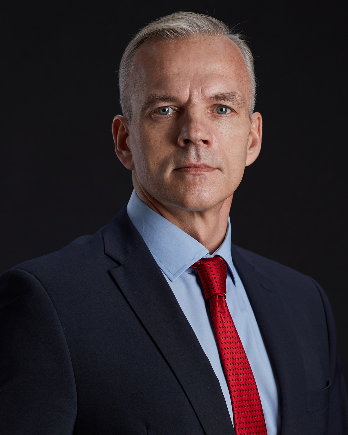 Professional portrait of handsome mature man looking at camera while standing against EU flag in background, copy space