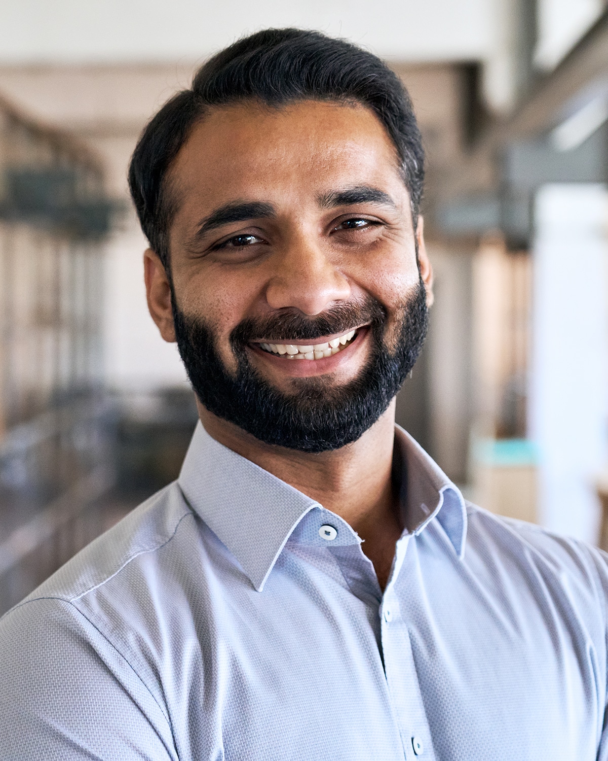 Happy smiling bearded indian business man small business owner, company leader or sales manager, male hispanic ceo executive, successful lawyer looking at camera standing in office, headshot portrait.